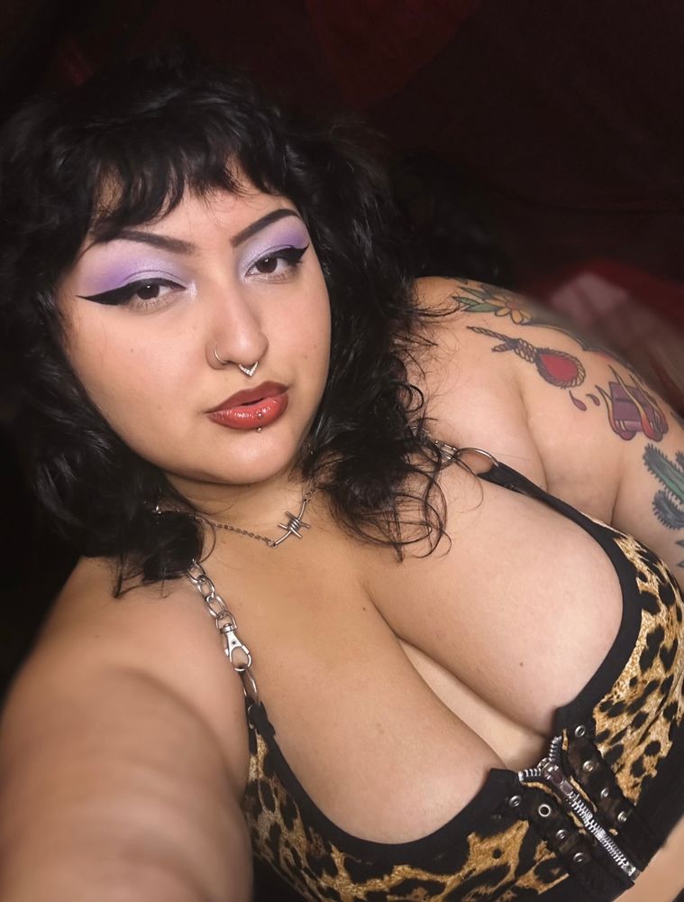 A selfie of Mistress Dahlia, eyes shimmering with a lavender eyeshadow, and of course a strong black winged eyeliner to compliment her dark eyebrows and lovely pinky red lips. 

She takes the selfie in a way that you can really be hypnotized by her enormous tits pouring out of a cheetah print top. 

You want to buy her the eyeliner, you want her to think of you and only you when she does her makeup. 