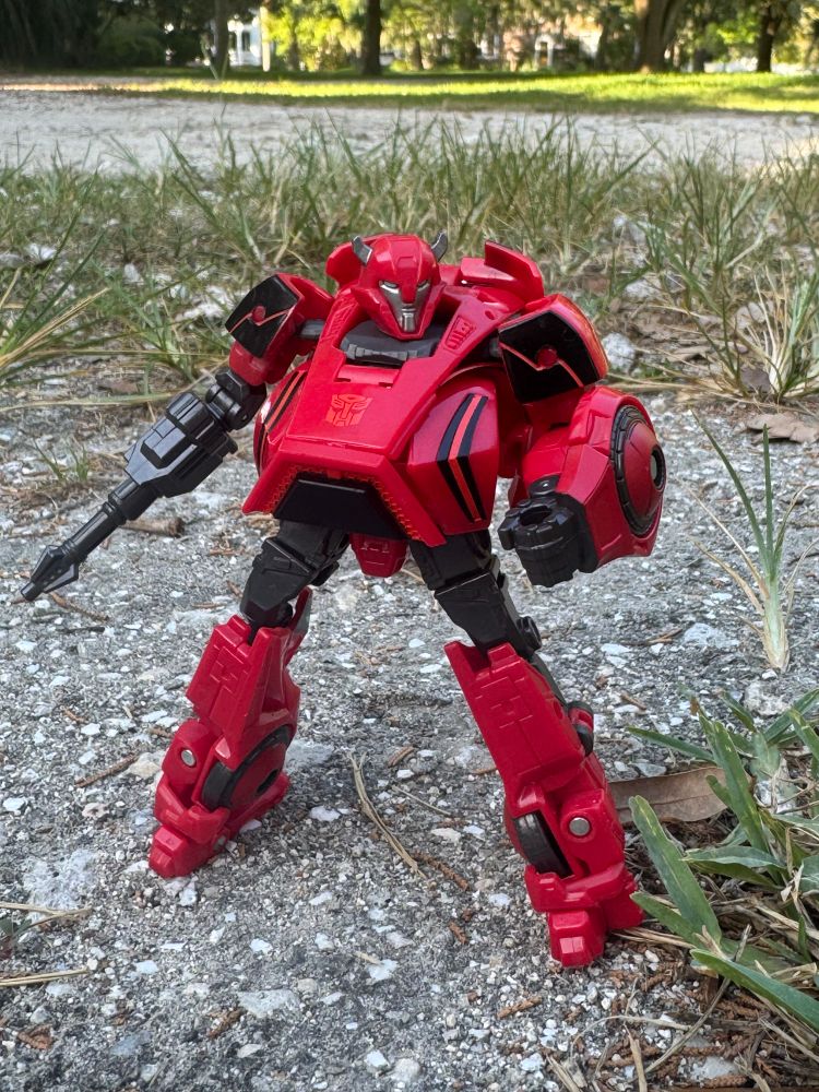 Cliffjumper with one of his arms replaced with a blaster standing in a patch of gravel.