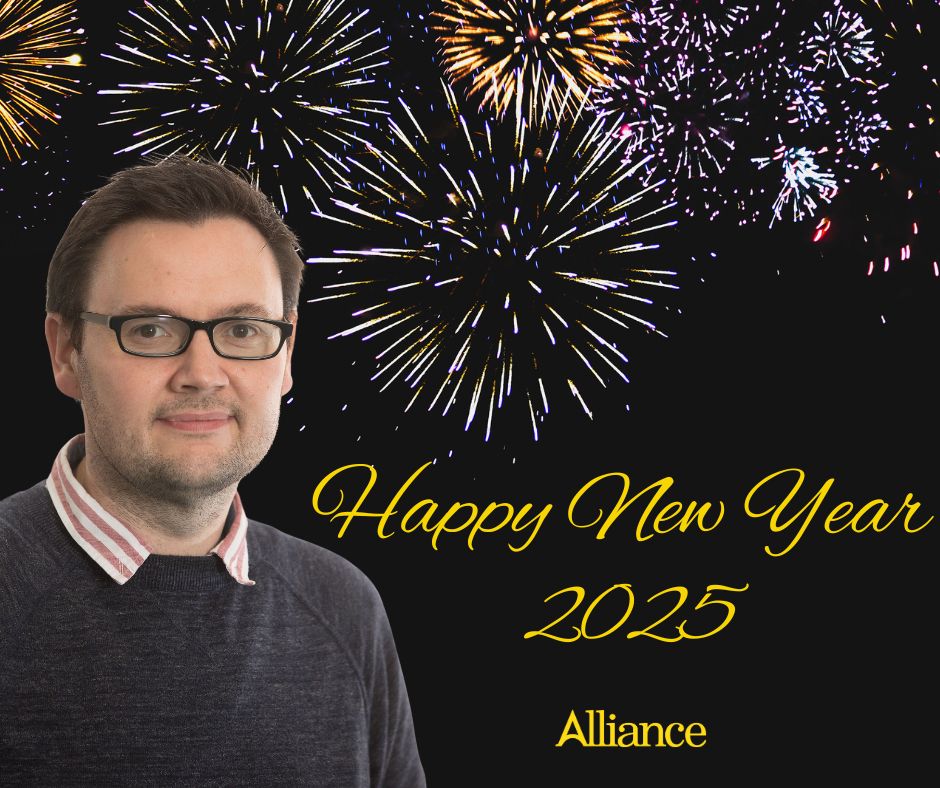 A night sky lit up with fireworks. On the left, a photo of me wearing my usual blue jumper and red-and-white striped shirt. Text reads: Happy New Year 2025. Underneath, the Alliance logo