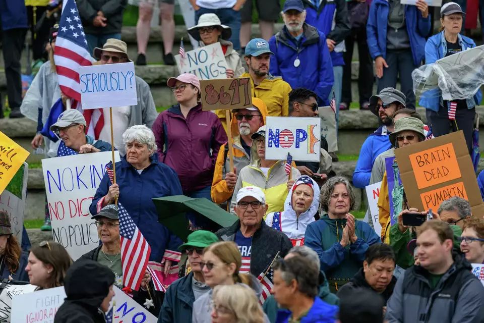 Photo from the No Kings protest on Saturday June 14, 2025. Photo was taken in Troy, NY and shows a crowd of people holding various signs and American flags. One woman in a blue shirt with white hair holds a sign that simply says "SERIOUSLY?" 