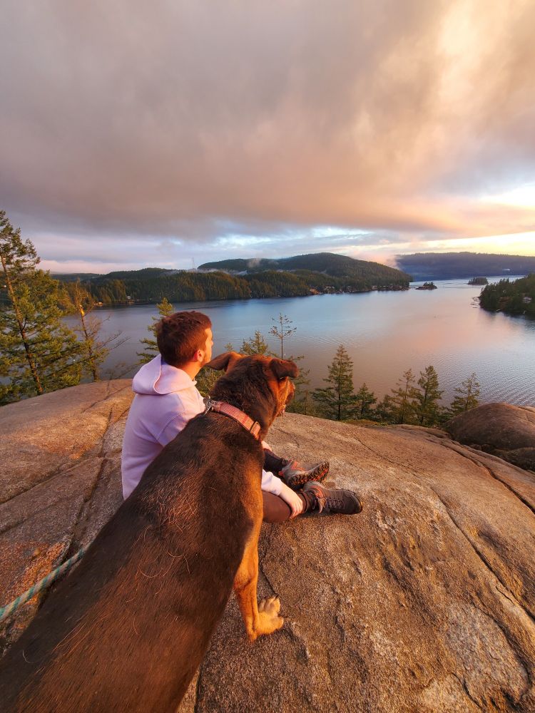 Max and my son overlooking a body of water from a very high up rock after a long hike
