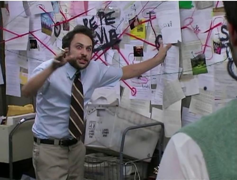 Charlie Day in It's Always Sunny, with a crazed look on his face, cigarette in hand, pointing at a wall of papers and lines connecting them like he's onto something 