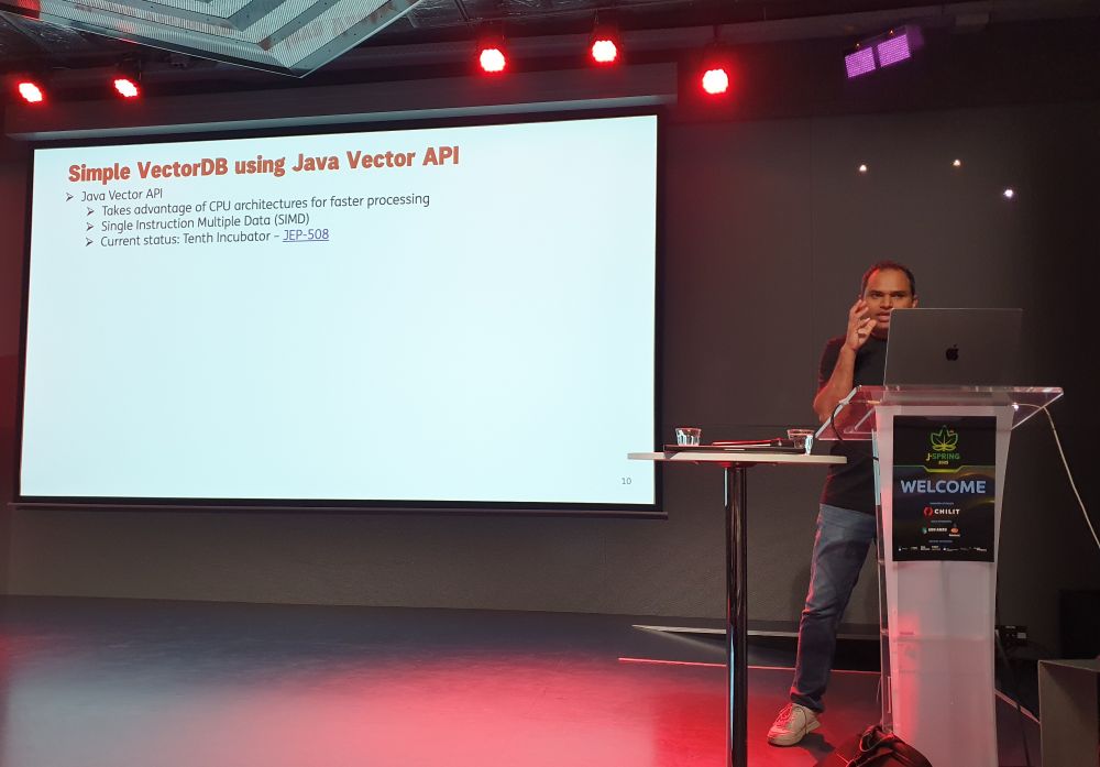 Bala Rawool on stage at JSpring in front of a slide about Java Vector API (JEP 508).