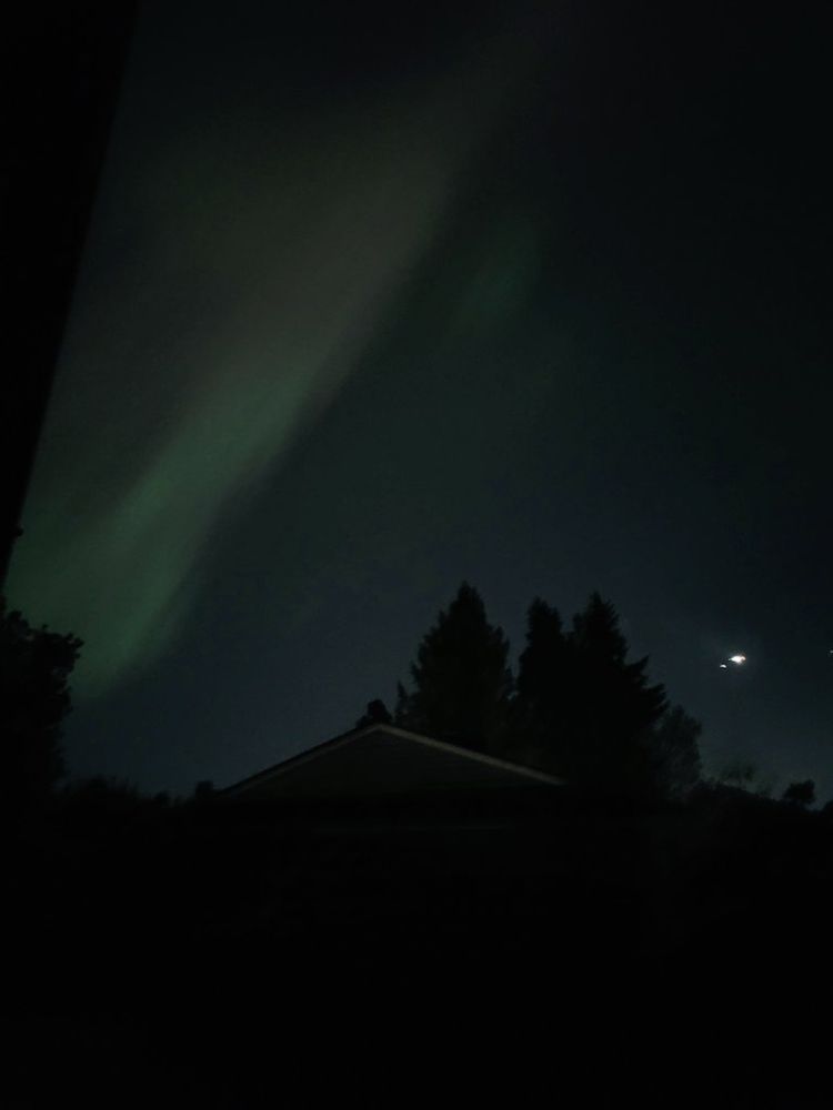 An image of the sky with a faint wispy green glow from the aurora borealis.