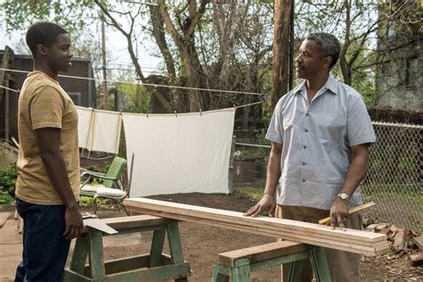 Still from the movie Fences with Troy (Denzel Washington) and Cory (Jovan Adepo) having a conversation in the backyard with wood planks atop sawhourses between them. In the background, there is laundry hanging on the clothesline to dry.