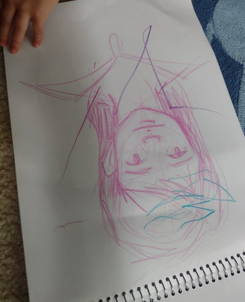 A crude pink crayon drawing of a woman, with a small child's hand touching the page of the sketchbook as though they're about to turn the page.
