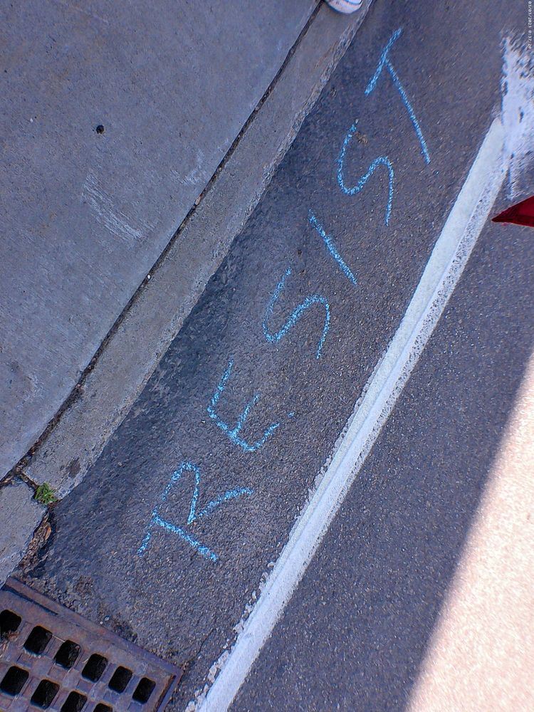 RESIST written in blue chalk in the 5 corners area in Vermont for no kings day on June 14, 2025. 