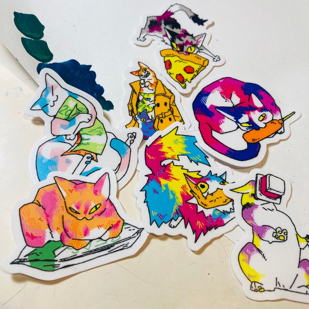 Photo of stickers of various cats stealing items such as yogurt, frozen peas and cash. The fur patterns are colourful and follow various pride flag colours.