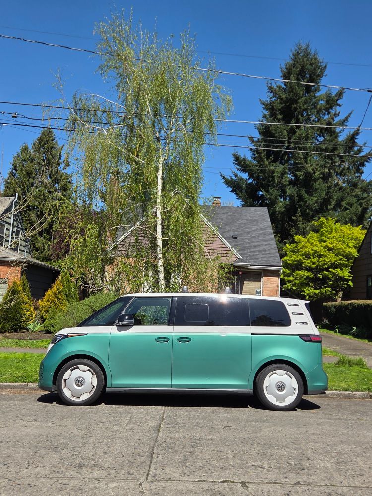 A VW ID Buzz in an aquamarine retro paint job, in a Portland neighborhood, in bright sunligh