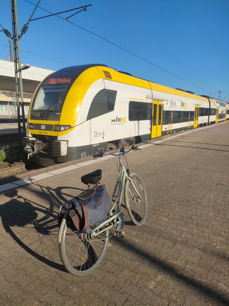 Photo du train RE7 à destination d'Offenburg en gare de Basel Bad. Un vélo est posé sur le quai devant le train.