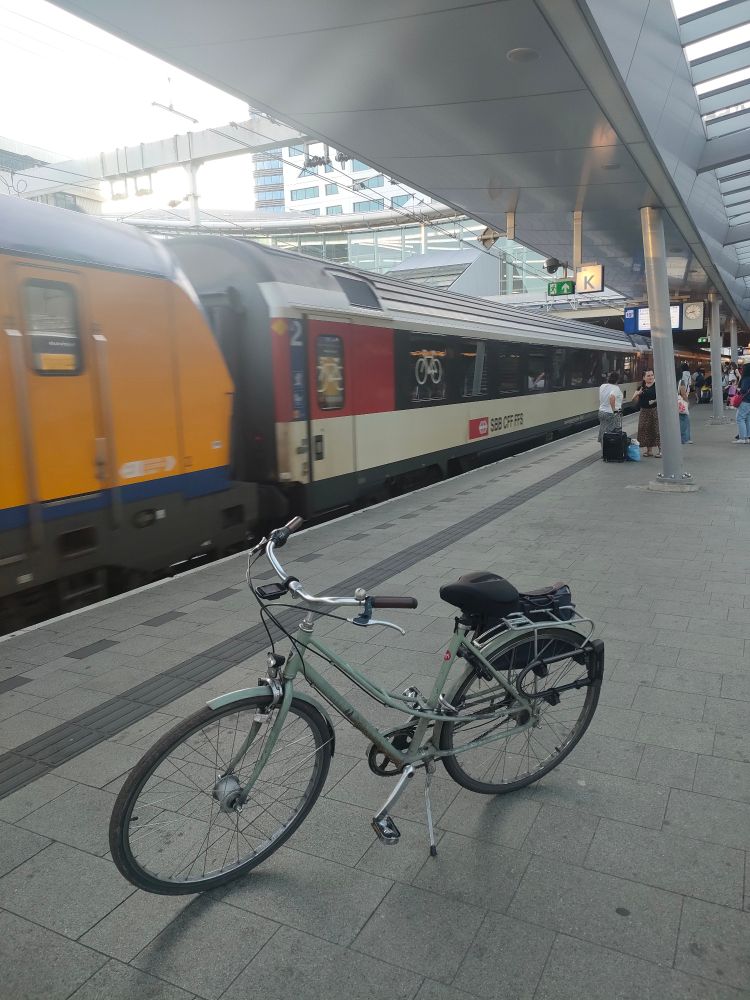 Photo du train NJ403 à son arrivée en gare d'Utrecht. On distingue l'arrière de la locomotive NS puis la première voiture sièges CFF. Un vélo est garé sur le quai au premier plan.