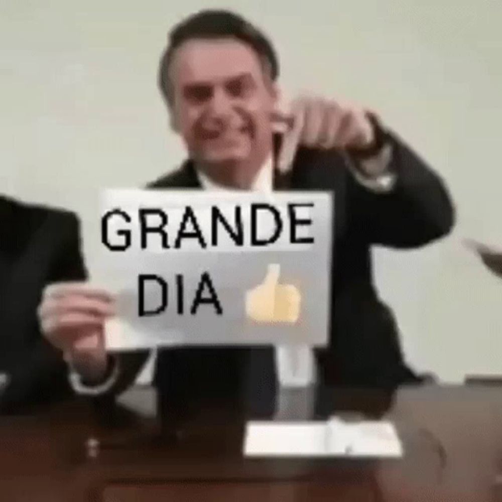 a man in a suit and tie is holding a sign that says grande dia and giving a thumbs up .