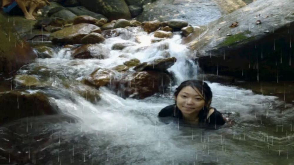 a woman is swimming in a stream with a dog behind her