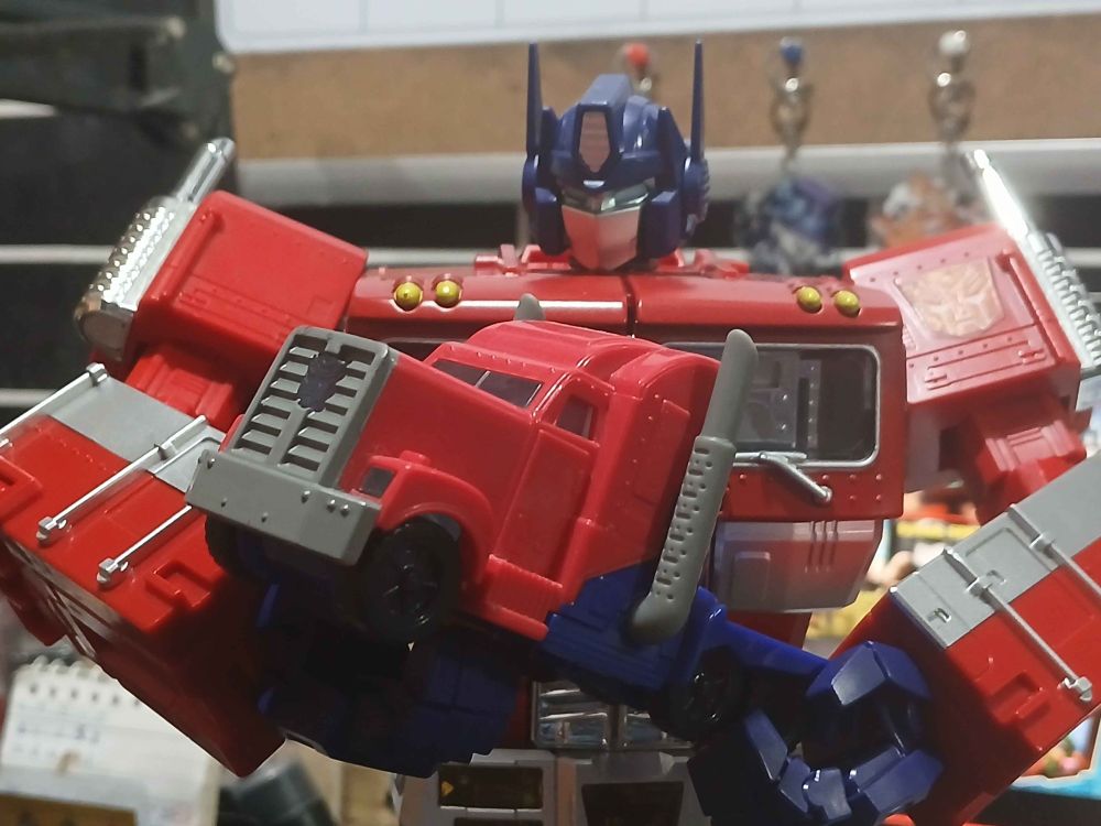 G1 Optimus Prime affectionately holding a Transformers Prime truck Optimus