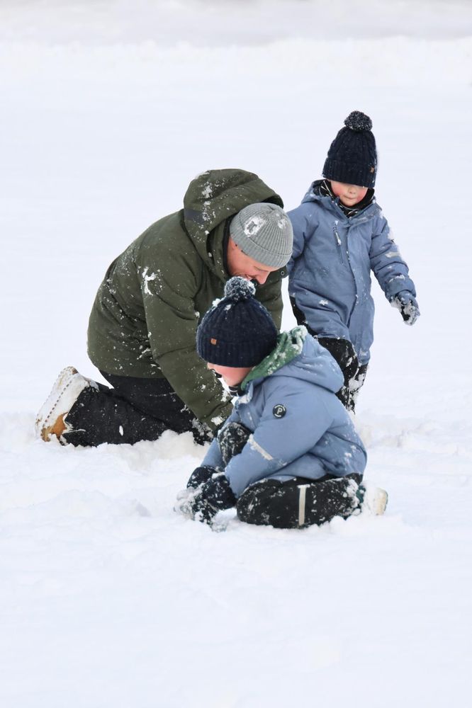 Me and my two oldest kids sitting in the snow and forming snowballs. Our clothes are covered with snow.