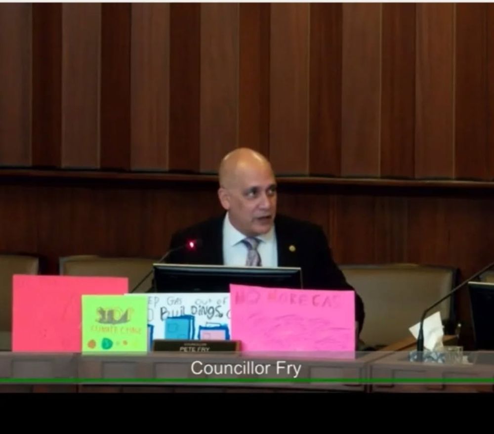 Pete Fry, with a bunch of colourful signs with hand-written slogans by literal children