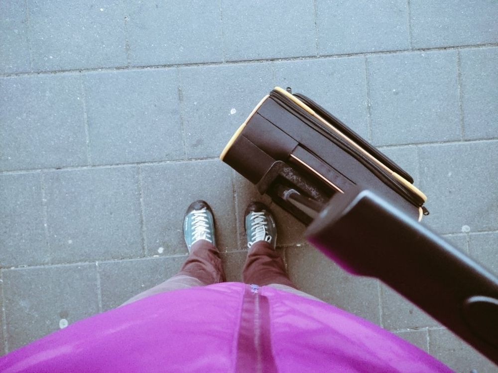 Meine Füße auf Beton, daneben ein Koffer