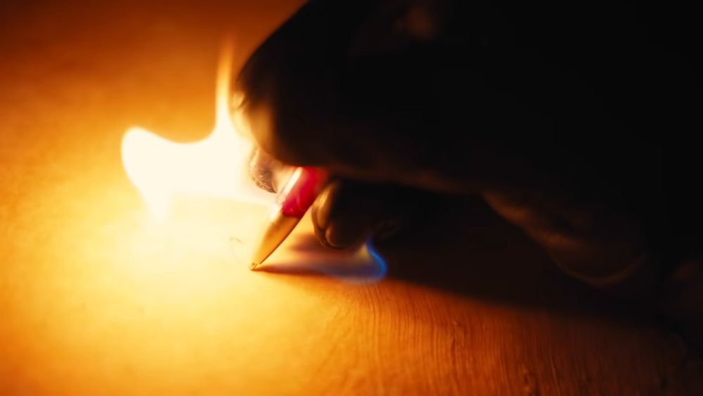 Meme picture of a hand writing with a flaming pen from Young Thug's "Hot" music video