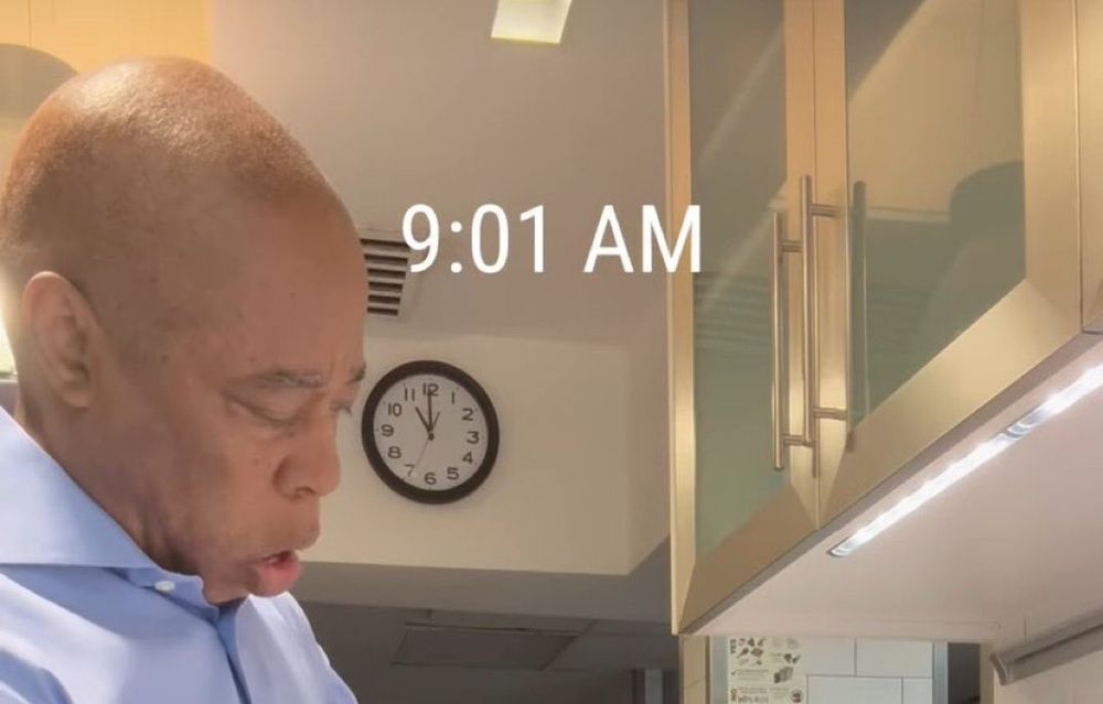 eric adams is pictured in front of a clock reading 11:00, with a text timestamp of 9:01 am 