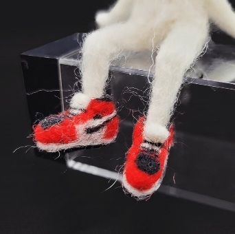 A closeup of his little red jordans. There are many tiny details, including a little tiny nike woosh.