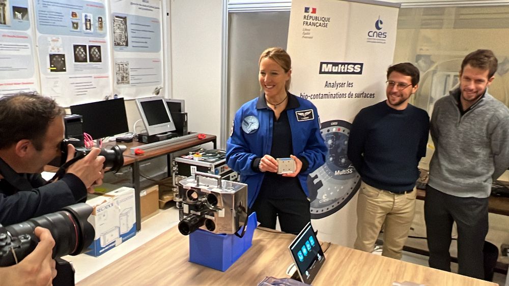 L'astronaute française Sophie Adenot pose avec deux collègues au Cadmos le laboratoire du CNES devant un dispositif scientifique MultiSS, entourée de matériel technique.