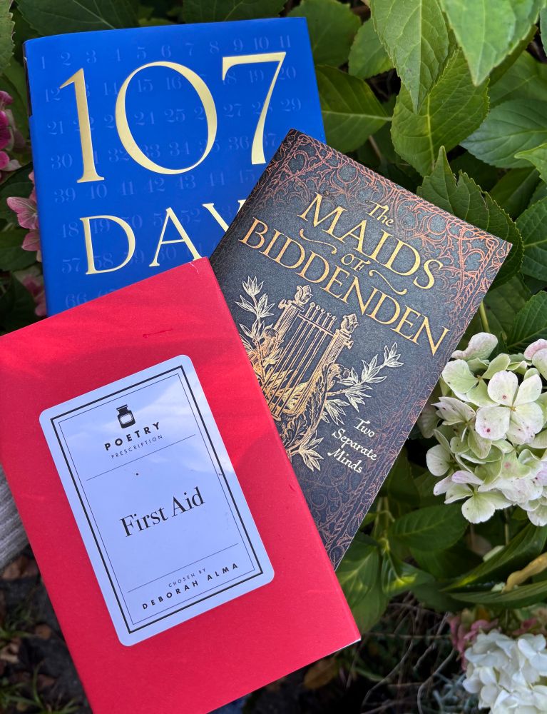 3 books surrounded by autumn hyacinths - 107 Days; Poetry Prescriptions First Aid; The Maids of Biddenden