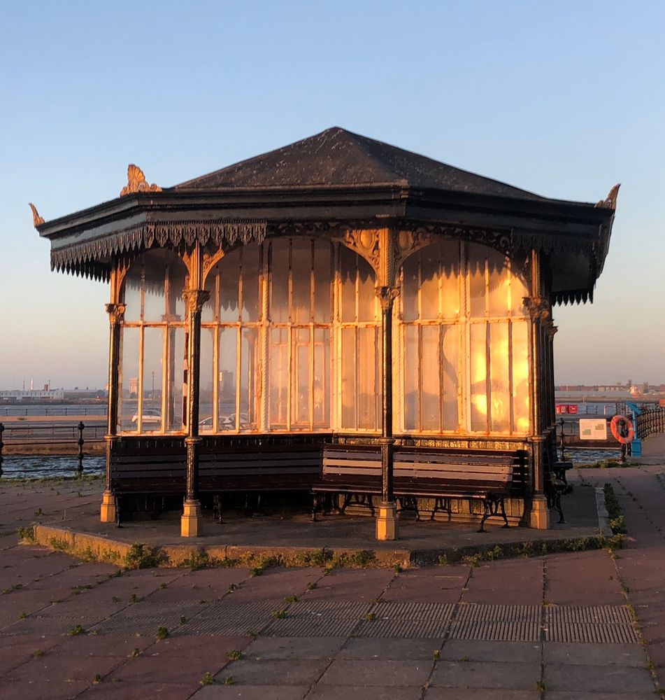 Setting sun reflected in the windows of a venerable seaside shelter. 