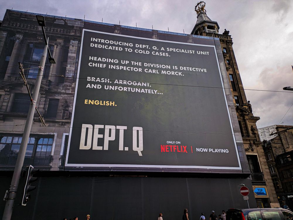 A huge billboard covering the entire side of a building. It advertises the TV show Department Q