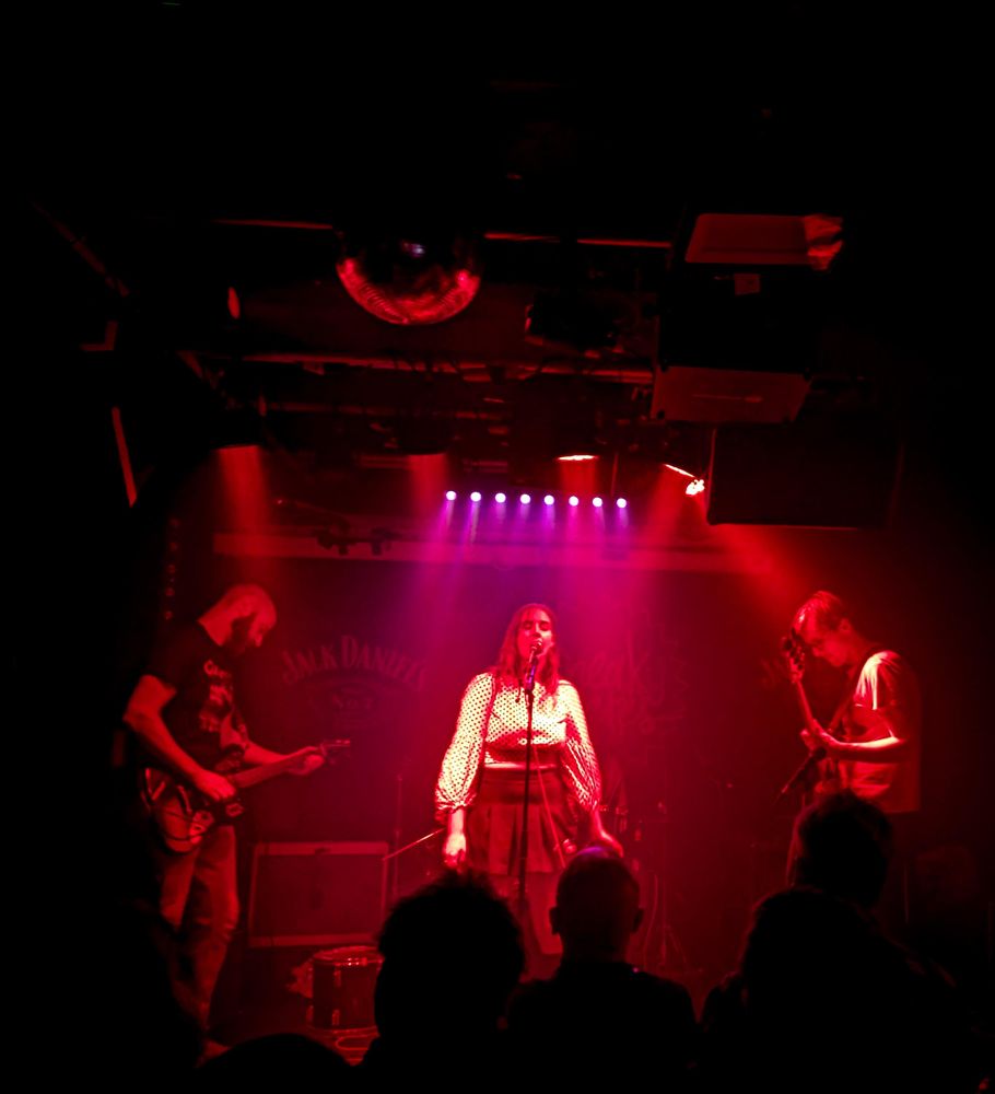 A band with female singer on stage with red lighting 
