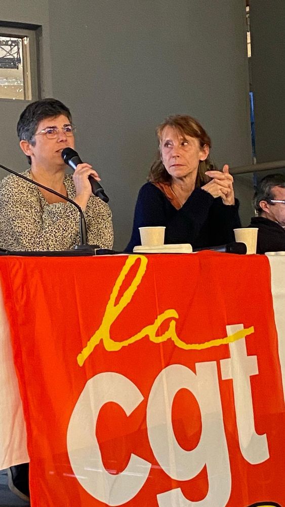 Photo d’une tribune avec un drapeau cgt educ et une militante qui prend la parole au micro 