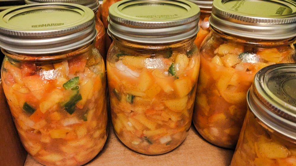 Peach salsa in jars on cardboard.