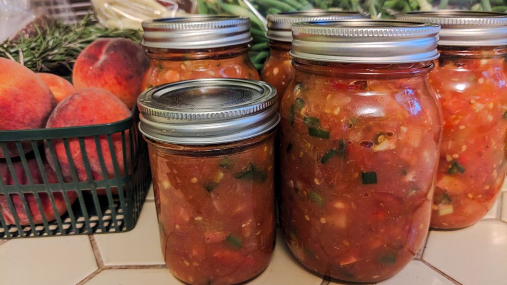 Salsa in canning jars on a yellow tiled kitchen counter.