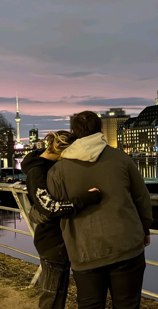 Me standing with my boyfriend at the Spree and in the Background you see the skyline of Berlin while sunset.