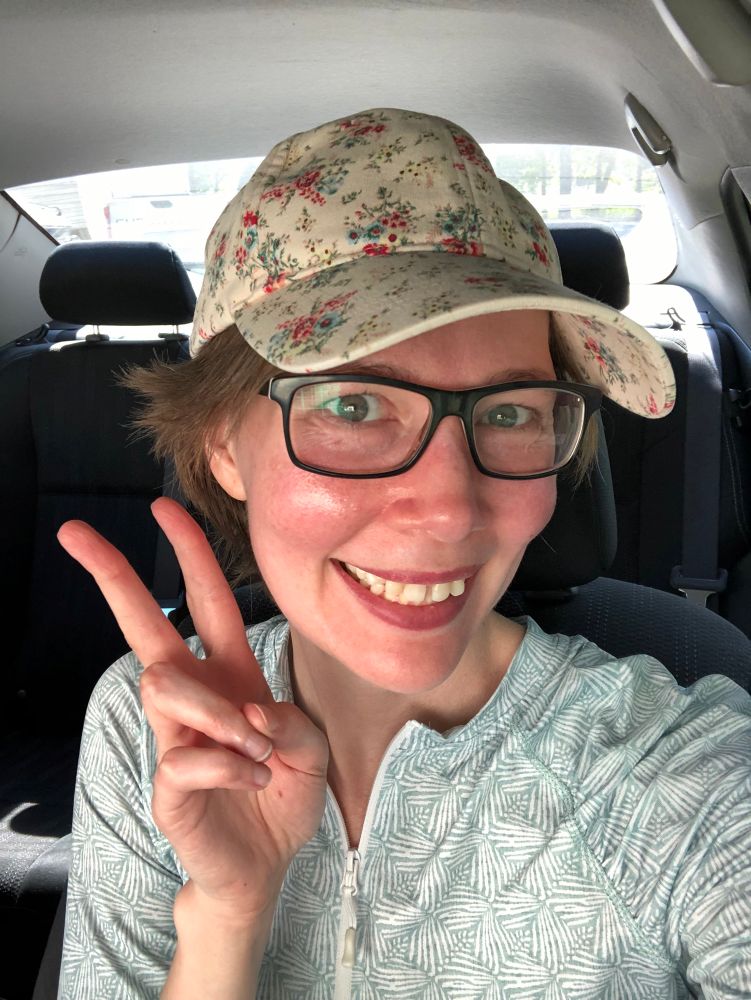 OP in their car, wearing a UV shirt and a baseball cap and flashing the peace sign