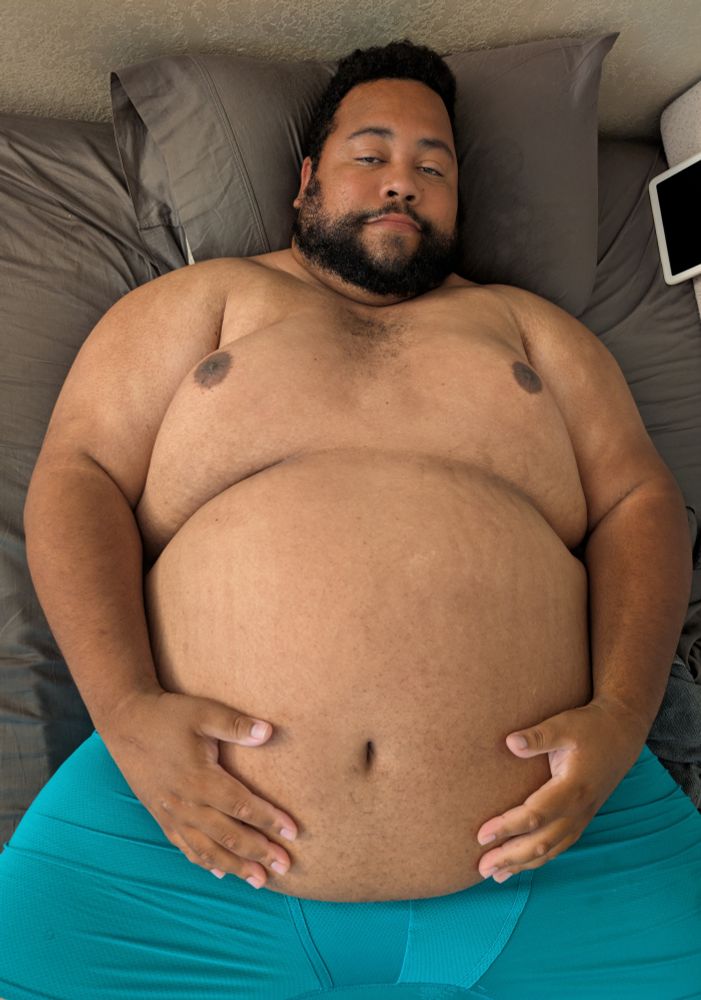 Superchub in his underwear laying shirtless in bed cradling his big belly in his arms 