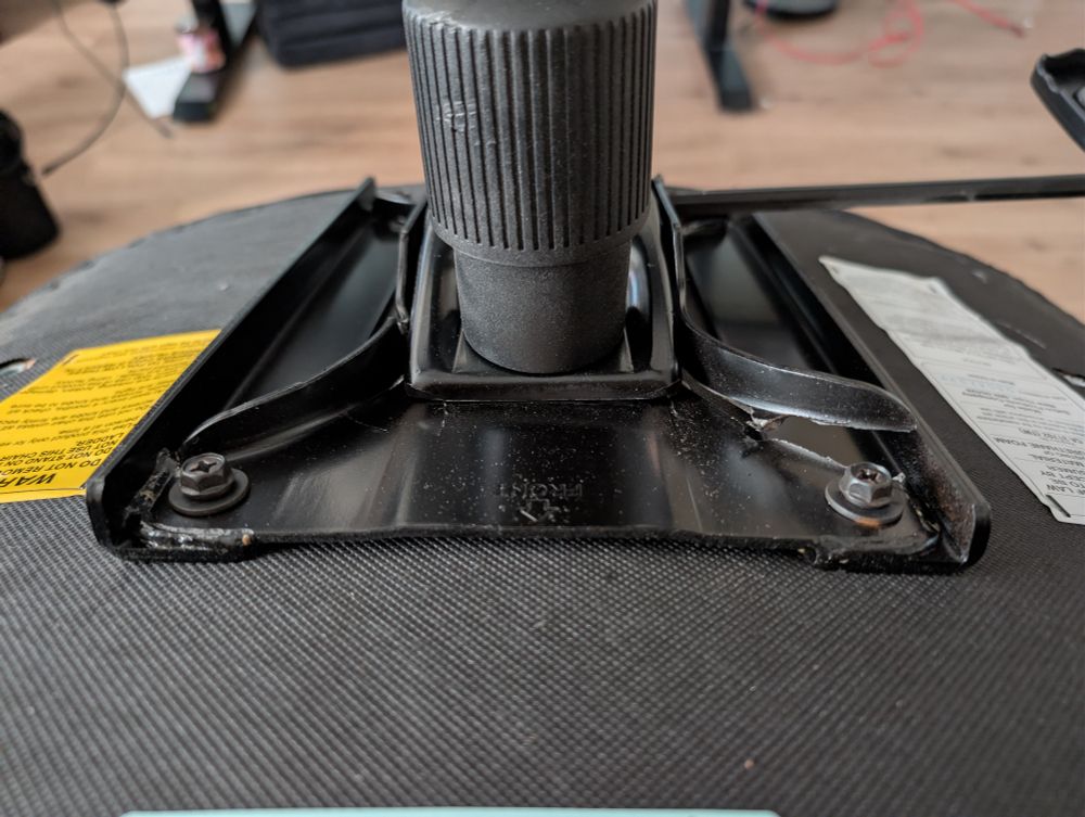 Underside of an office chair metal supports on the baseplate broken on one side 