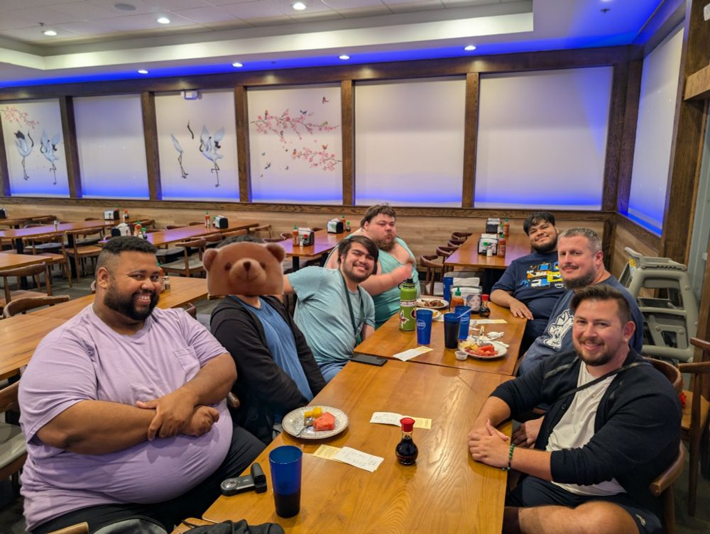 Seven people sitting down at a large dining table in a buffet 