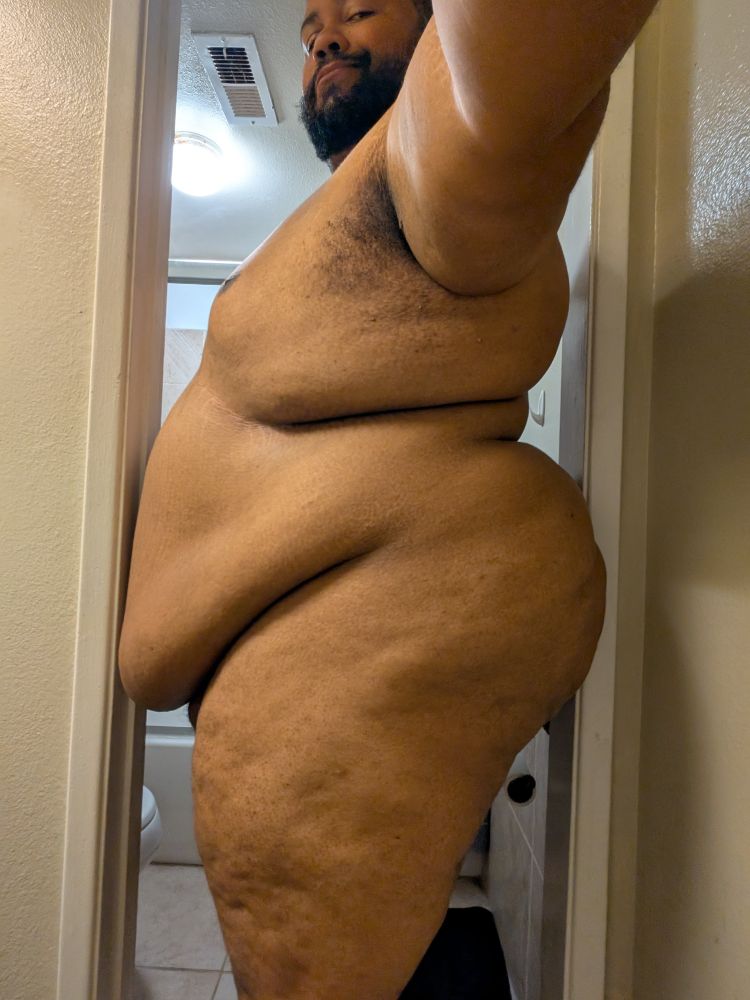 Nude superchub standing sideways in a narrow doorframe both his belly and massive ass touching the sides 