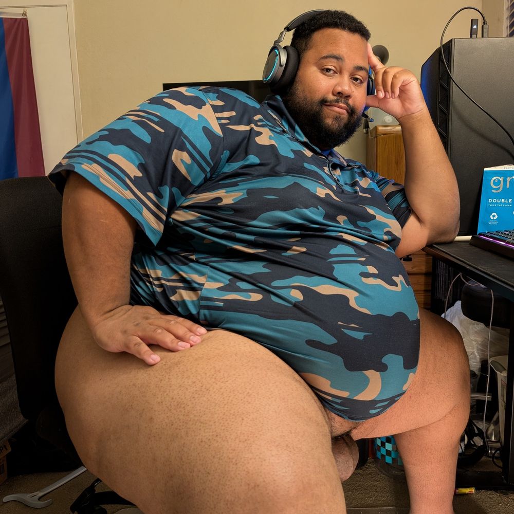 Superchub sitting in an office chair with one hand on his massive thigh only wearing a shirt you can see his fupa and pumped balls 