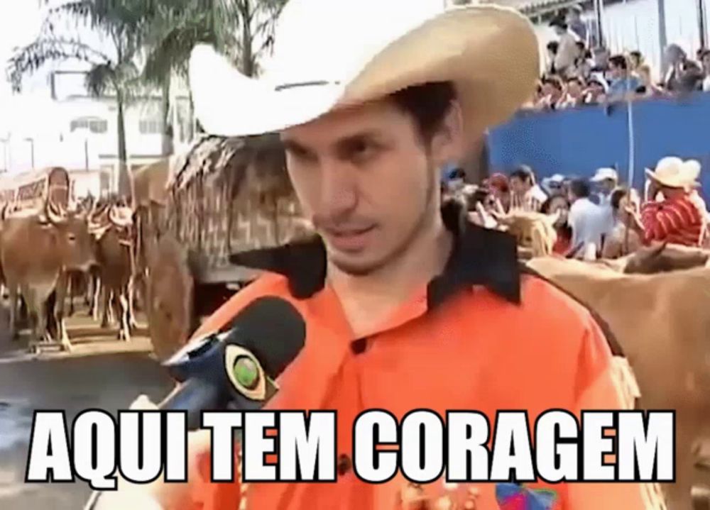 a man wearing a cowboy hat is talking into a microphone and the words aqui tem coragem are on the screen