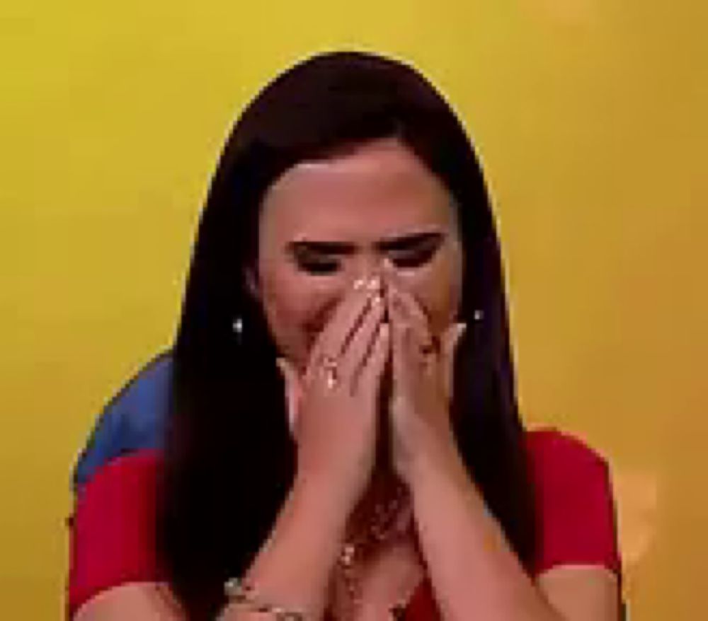 a woman is covering her face with her hands and crying .