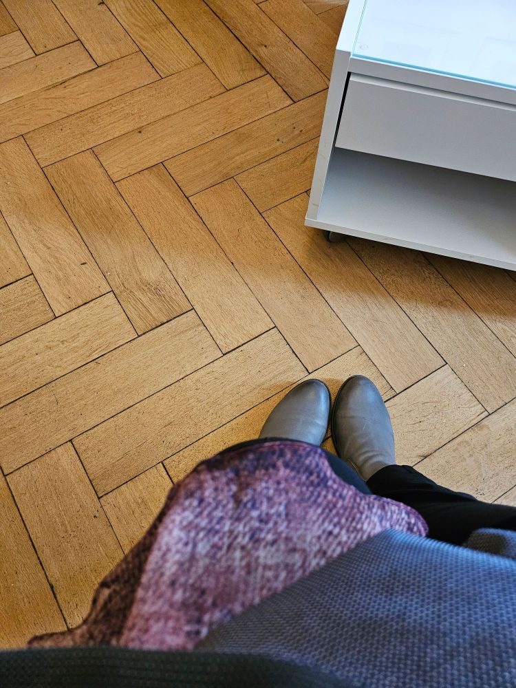 Parkettboden, ein weißer Tisch, meine Füße