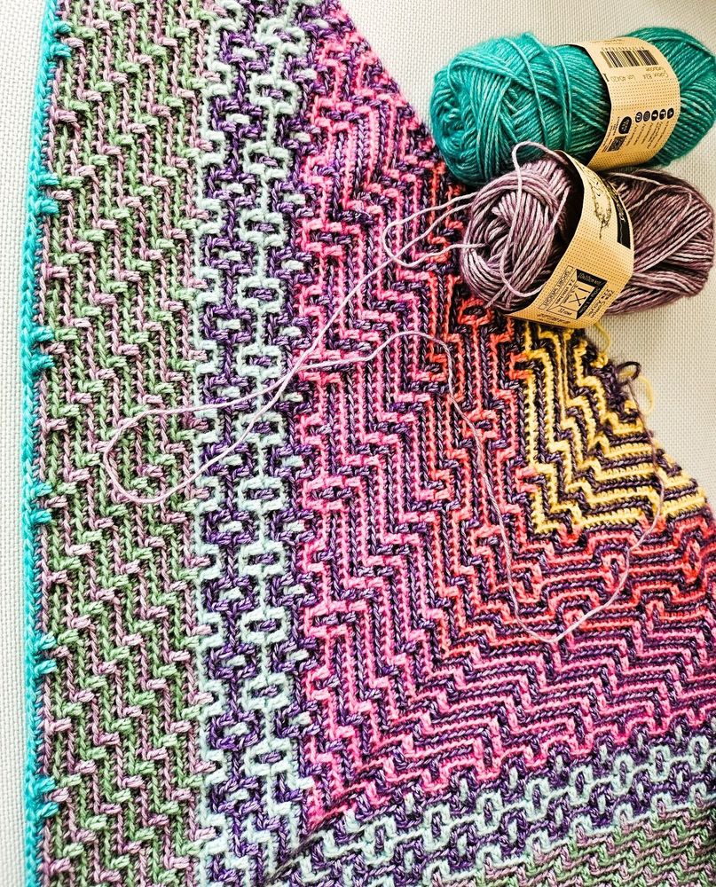 colorful crocheted shawl in mosaic technique, 2 balls of the wool used are on the side