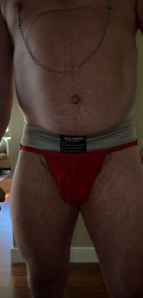 precumming through a red jock with nipple clamps on
