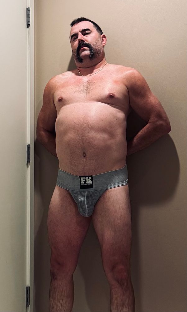 nude shot in a gray jockstrap, chastity cage bump visible 