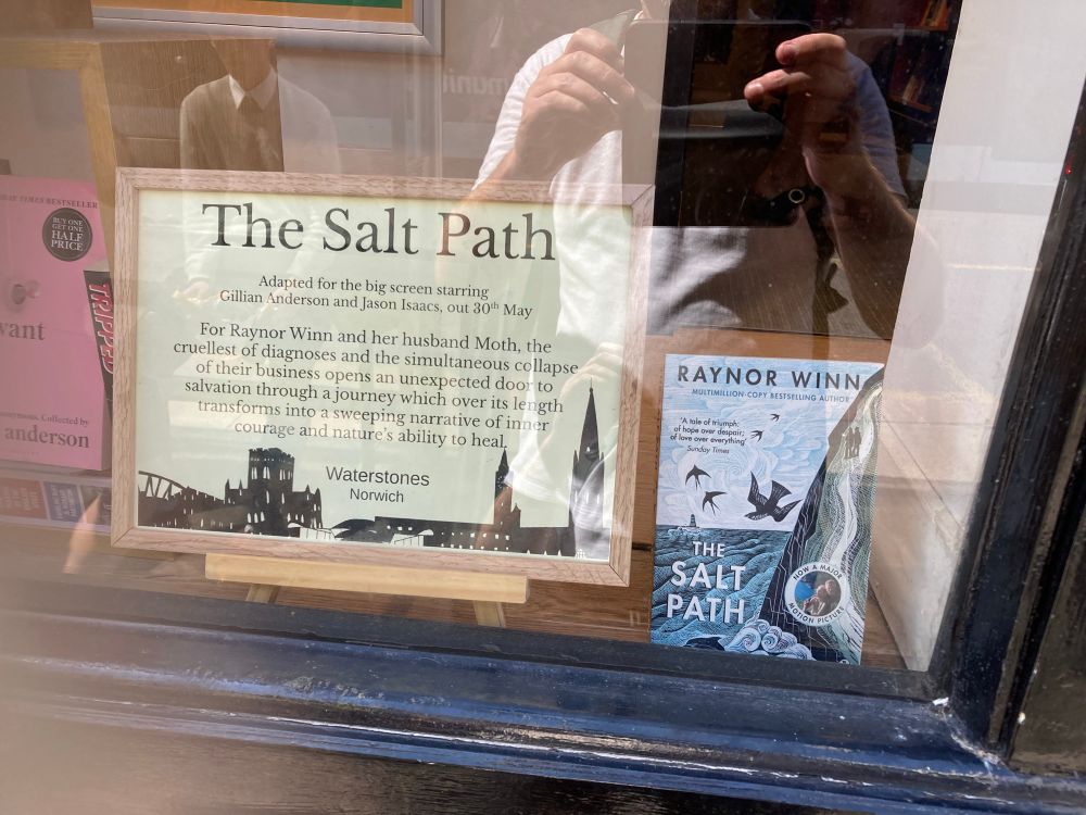 Promo text beside copy of the salt path in a Waterstones shop window on Friday 18th July, as if the grand unmasking of the author’s real story never happened 