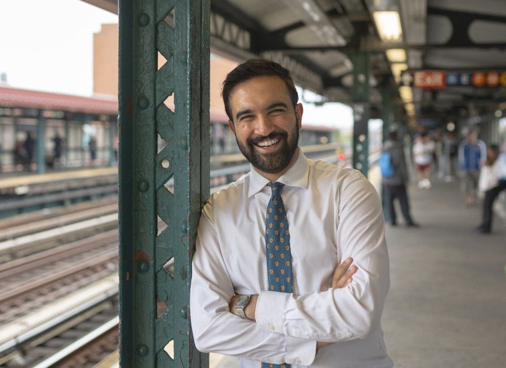 Zohran Mamdani smiling on a train platform