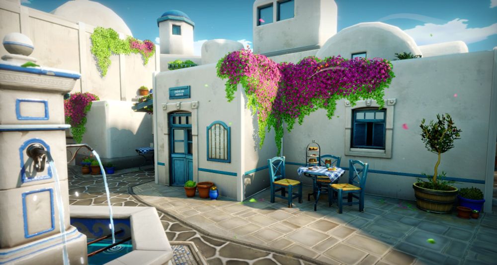 A wide-angle screenshot of my Greece scene. In the picture there are white, bulky buildings with blue accents marking the doors, windows and distant, round rooftops. From the buildings there are large groups of pink flowers growing. In the middle of the scene stands a fountain that ties the street scene together. Along one of the corners there is a small, blue table set with some Greek treats sitting on the table.