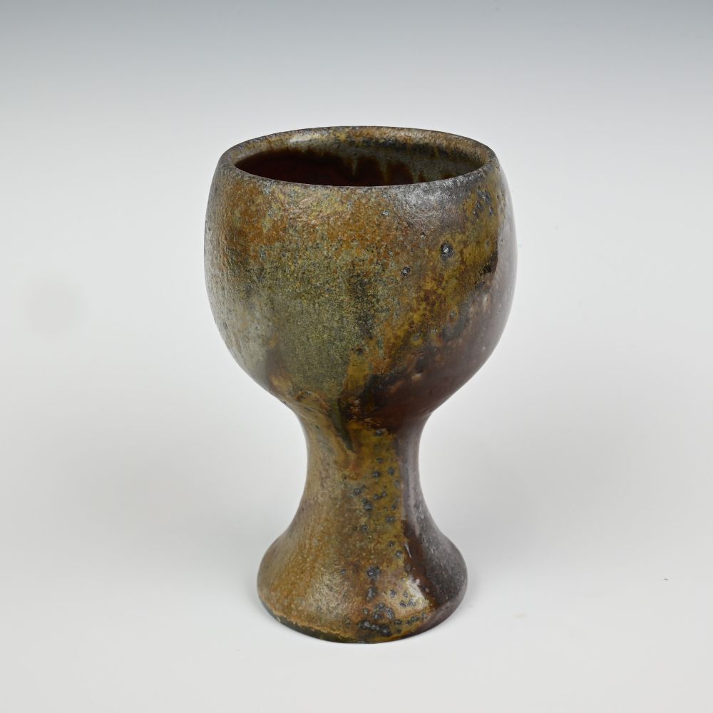 A goblet shaped wood fired ceramic cup, with heavy wood ash.