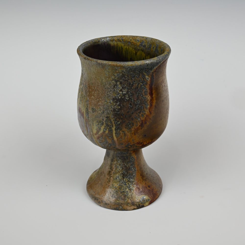 A tulip shaped wood fired ceramic cup, with heavy wood ash.